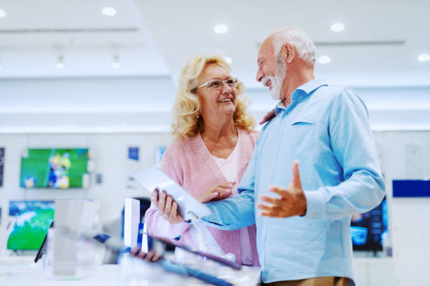 istock Happy smiling senior choosing new tablet while standing in tech store. 1149441945