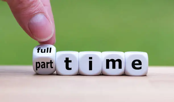 Hand is turning a dice and changes the word "full-time" to "part-time" (or vice versa).