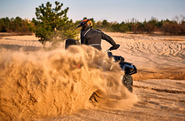 Racing powerful quad bike on the difficult sand in the summer. Racing in the sand on a four-wheel drive quad. 4 wheel motorbike stock pictures, royalty-free photos & images