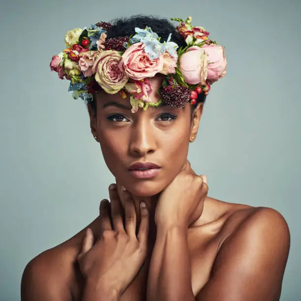 Studio portrait of a beautiful young woman wearing a floral head wreath against a grey background