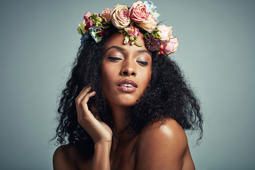 Studio shot of a beautiful young woman wearing a floral head wreath against a grey background