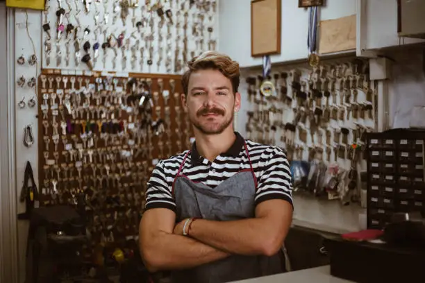 Authentic young locksmith posing in his shop