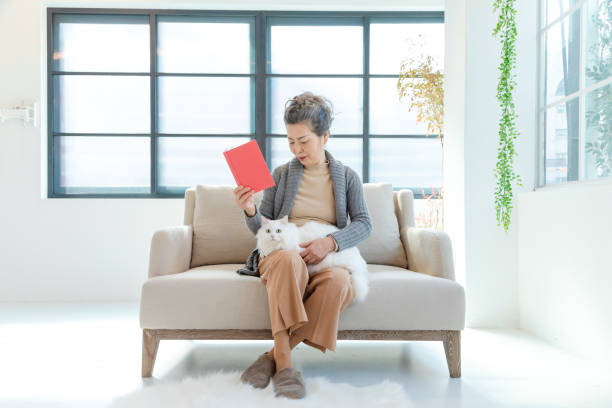 istock Senior women looking at white cat on the sofa 1149461161