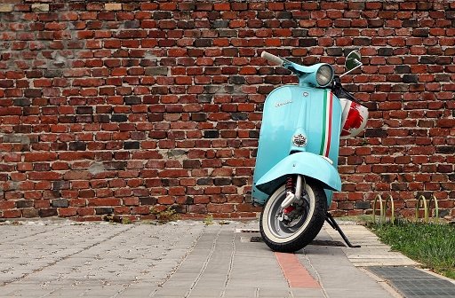 Udine,Italy. May 14 2019. An iconic vintage blue Vespa scooter parked. Old brick wall on background