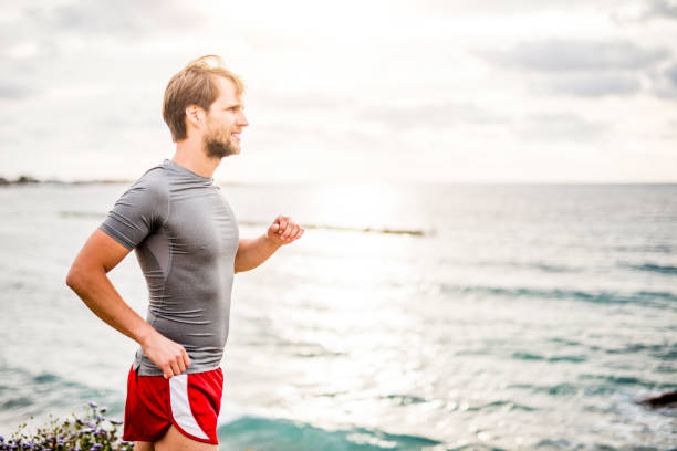 istock Young man running by the sea. 1149473409