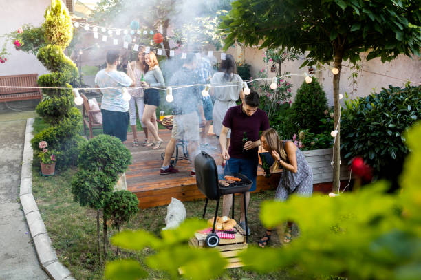 Summer party outdoors Group of pretty young people have barbecue party in a backyard garden parties stock pictures, royalty-free photos & images