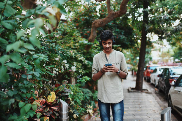istock Teenage boy using mobile phone while walking on the street 1149481525