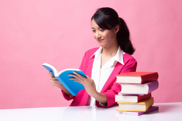 istock Young Asian woman read a book with books on table. 1149485201
