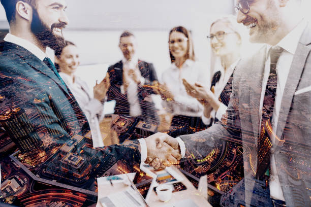 istock Two successful businessmen shaking hands while other colleagues clapping. Double exposure technique used. 1149485900