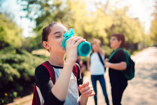 schoolgirl drinking water at schoolyard - water bottle water bottle drinking imagens e fotografias de stock