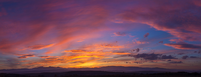 Wide high view of a mountain sunset with dramatic sky panorama.