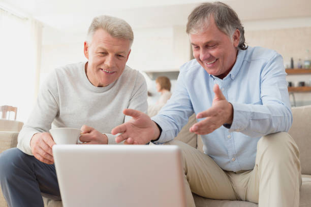 istock Smiling mature men using laptop while sitting at home 1149497912