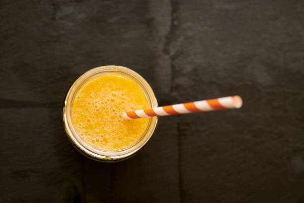 istock Mason Jar filled with fresh Orange Juice, with straw on a slate background. 1149501274