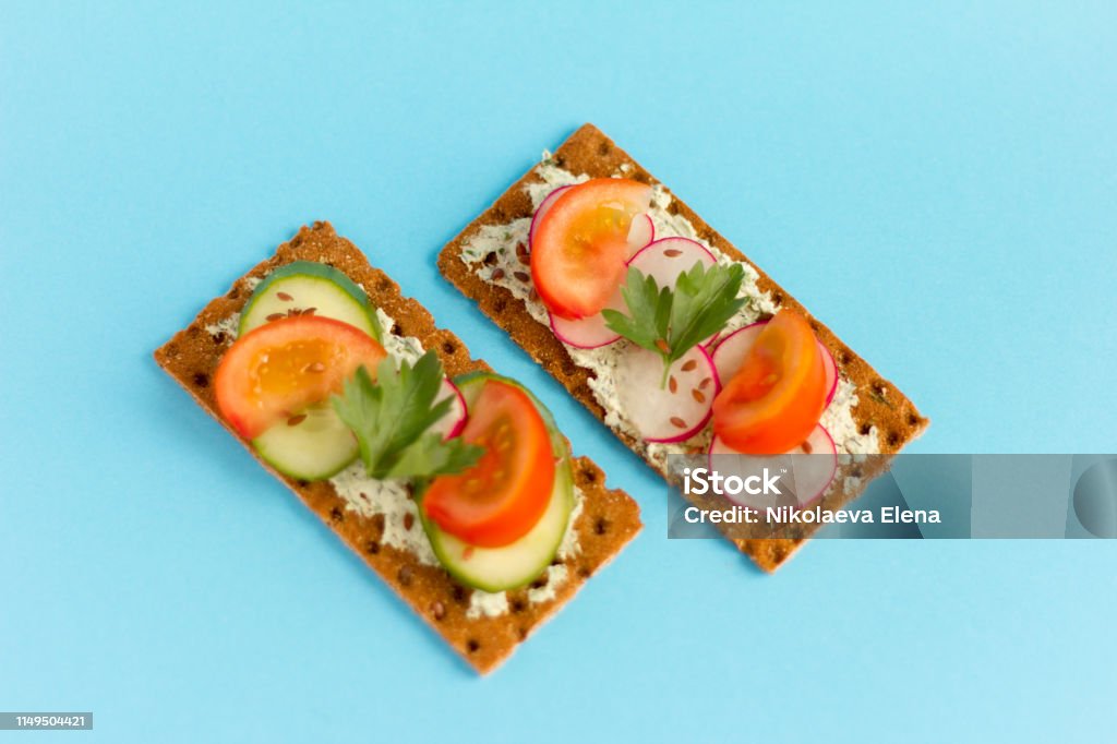 delicious summer sandwiches with cottage cheese with greens and vegetables on a blue background Above Stock Photo