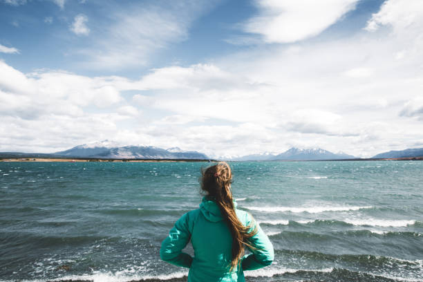 woman looking at the ocean and mountains in puerto natales, patagonia - horizon over water white green blue imagens e fotografias de stock