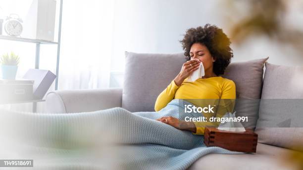 Woman Sneezing In A Tissue In The Living Room Stock Photo - Download Image Now - Cold And Flu, Illness, Flu Virus