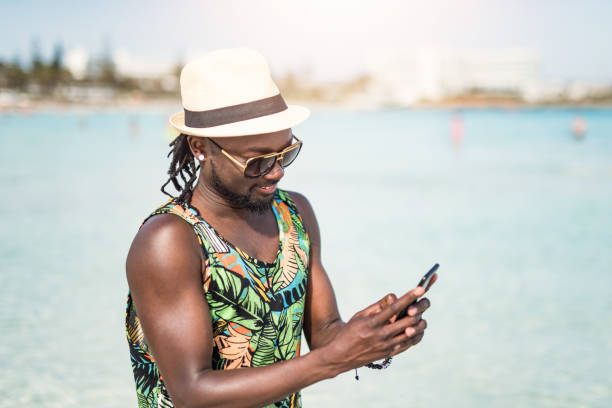 istock Happy African man enjoying a vacation on a beautiful beach and using phone. 1149519183