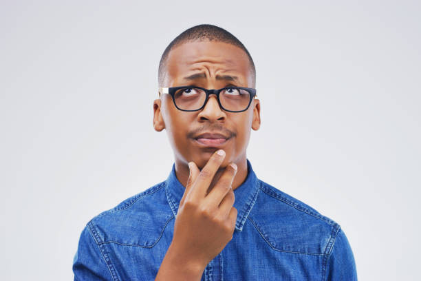 This puts me in a awkward position Studio shot of a young man looking thoughtful against a gray background man thinking stock pictures, royalty-free photos & images