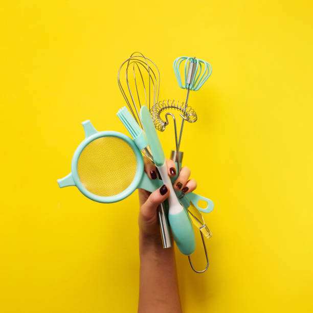 istock Baking flat lay. Female hands holding kitchen tools, sieve, rolling pin, spatula and bruch on yellow background. Banner with copy space. Top view. Square crop 1149522765