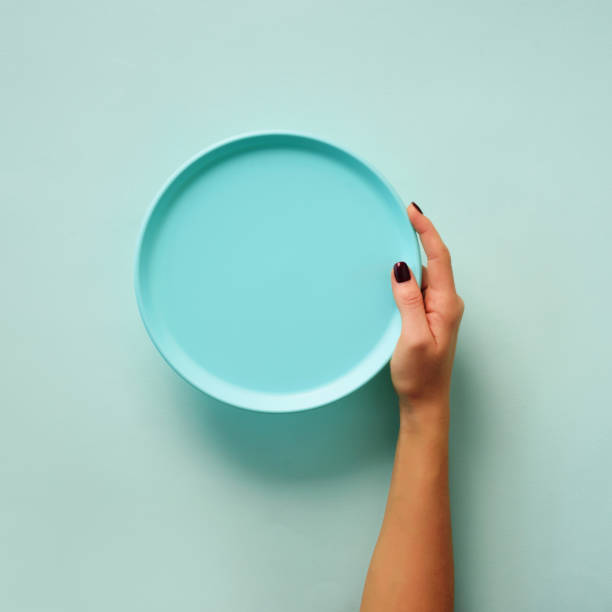 istock Female hand holding empty blue plate on pastel background with copy space. Healthy eating, dieting concept. Banner 1149522781