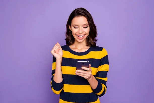 Close up photo beautiful amazing she her lady hands hold telephone reader news information amazed excited big surprise shock omg wow wear blue yellow striped pullover isolated violet purple background.