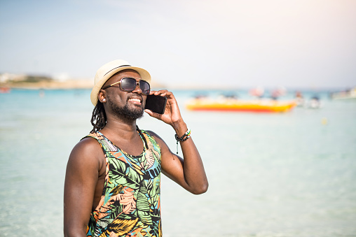 African man on a vacation using phone.