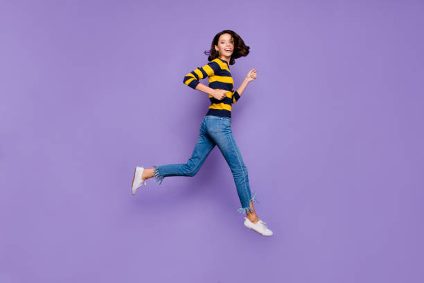 longitud completa del perfil del cuerpo del tamaño de la foto hermosa ella su dama alegre salto de alta prisa venta de compras de descuento centro comercial tienda de ropa de color amarillo azul con un fondo morado violeta aislado - jumping women running vitality fotografías e imágenes de stock