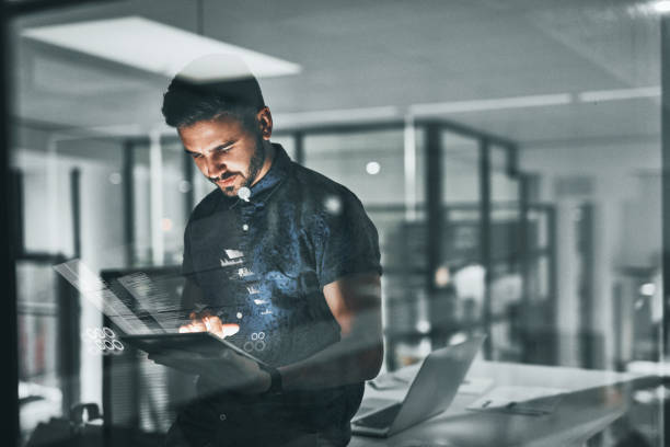 Overtime is something all successful people must do Cropped shot of a handsome young businessman working late in the office touch screen photos stock pictures, royalty-free photos & images