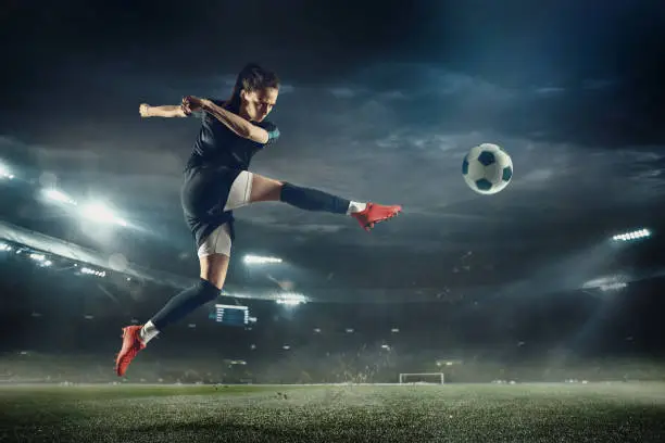 Photo of Female soccer player kicking ball at the stadium