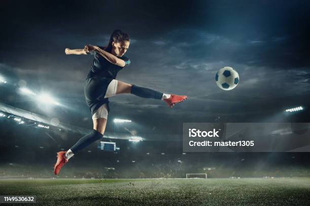 Foto de Jogador De Futebol Fêmea Que Retrocede A Esfera No Estádio e mais fotos de stock de Futebol