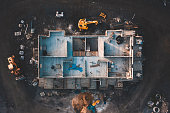 Aerial top down shot of a house frame on a construction site surrounded by mud