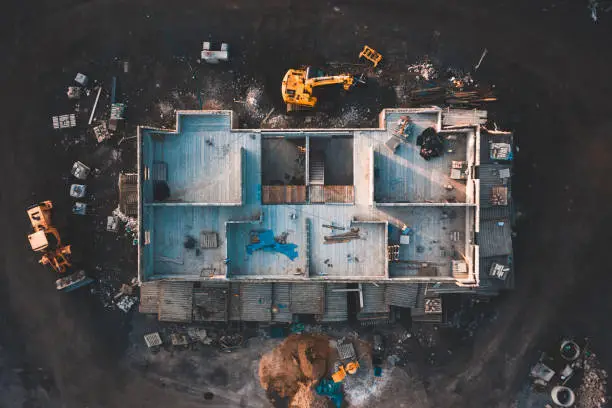 Photo of Aerial top down shot of a house frame on a construction site surrounded by mud