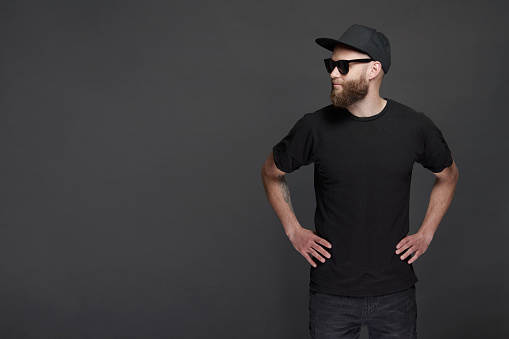 Hipster handsome male model with beard wearing black blank baseball cap with space for your logo