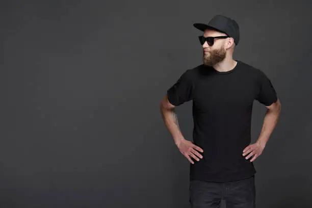 Photo of Hipster handsome male model with beard wearing black blank baseball cap with space for your logo