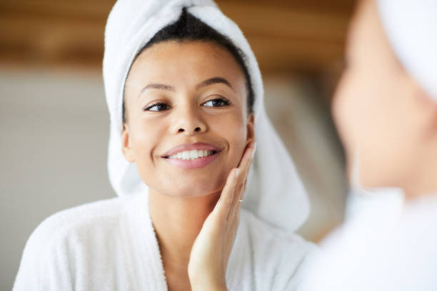 Fresh Skin Head and shoulders portrait of  smiling Mixed-Race woman looking in mirror during morning routine, copy space towel photos stock pictures, royalty-free photos & images