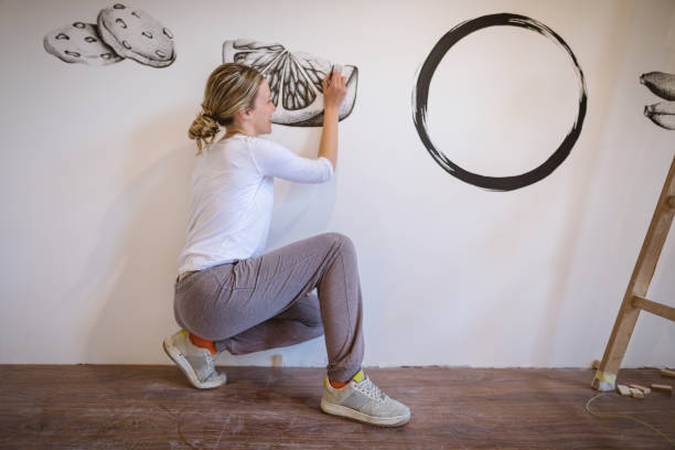 istock Smiling blonde artist painting fruit on her white wall 1149536493