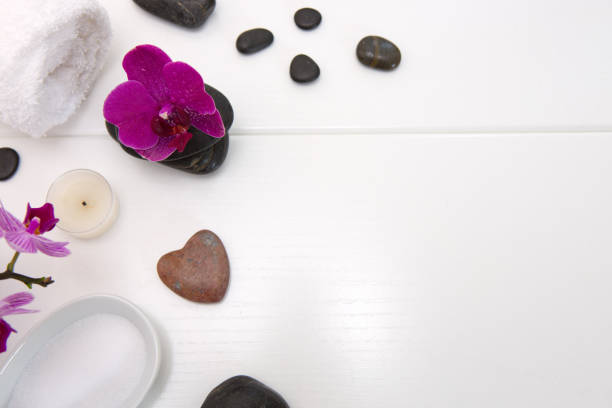 Spa or wellness setting with pink orchids ,candle and black stones.