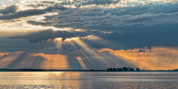 Sunbeam over lake with dramatic orange colored cloudscape. Location: Lake Steinhude, Lower Saxony, Germany.