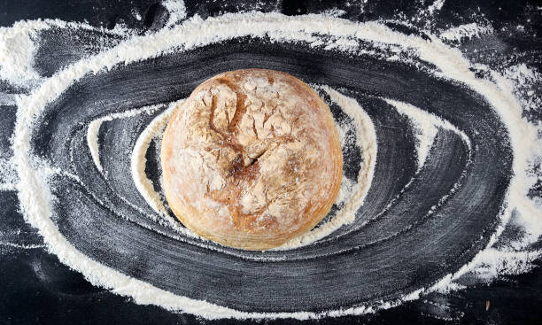 istock round baked bread and white wheat flour scattered on a black table 1149542712