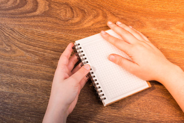 White notebook in hand on  a brown color background