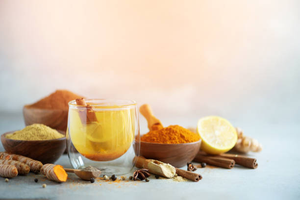 ingredienti per tè caldo alla curcuma su sfondo grigio. bevanda ayurvedica sana con limone, zenzero, cannella, curcuma. rimedio di potenziamento immunitario - zenzero spezie foto e immagini stock