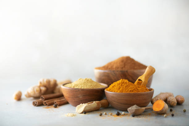 Ingredients for turmeric latte. Ground turmeric, curcuma root, cinnamon, ginger, black pepper on grey background. Spices for ayurvedic treatment. Alternative medicine concept stock photo