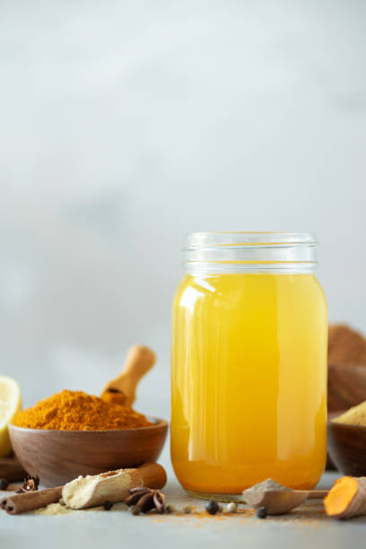 Ingredients for orange turmeric drink on grey concrete background. Lemon water with ginger, curcuma, black pepper. Vegan hot drink concept