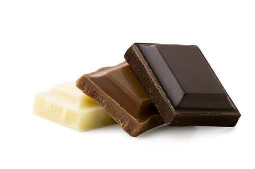 Dark, milk and white chocolate squares isolated on white. Rough edges.