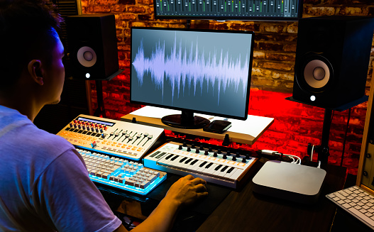 Sound technician at work sitting in front of the sound mixing table with headphones on listening to the music and making adjustments.