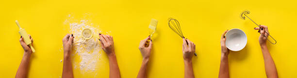 istock Female hands holding kitchen tools, sieve, rolling pin, bowl, sieve, brush, whisk, spatula for baking and cooking over yellow background. Food frame, bake concept with copy space 1149547109