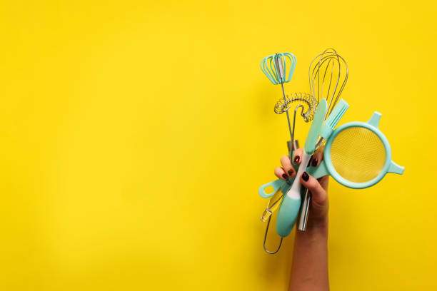 istock Baking flat lay. Female hands holding kitchen tools, sieve, rolling pin, spatula and bruch on yellow background. Banner with copy space 1149547151