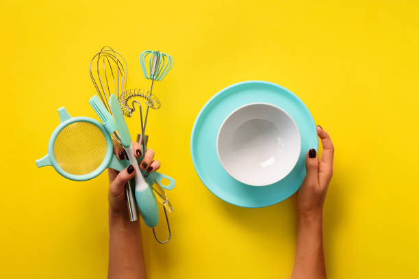 istock Woman hand holding kitchen utensils on yellow background. Baking tools - brush, whisk, spatula. Bakery, cooking, healthy homemade food concept. Copy space 1149547167