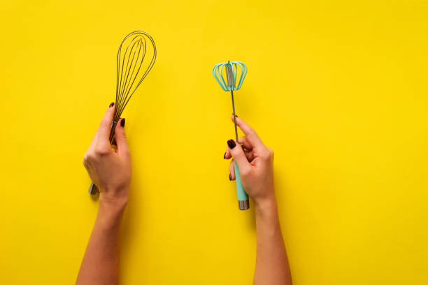 istock Woman hand holding kitchen utensils on yellow background. Baking tools - brush, whisk, spatula. Bakery, cooking, healthy homemade food concept. Copy space 1149547197
