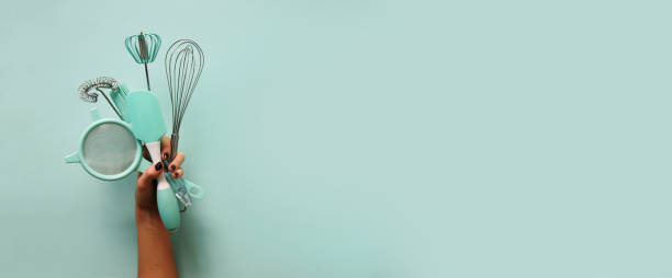 istock Baking flat lay. Female hands holding kitchen tools, sieve, rolling pin, spatula and bruch on pastel blue background. Banner with copy space. Top view 1149547206